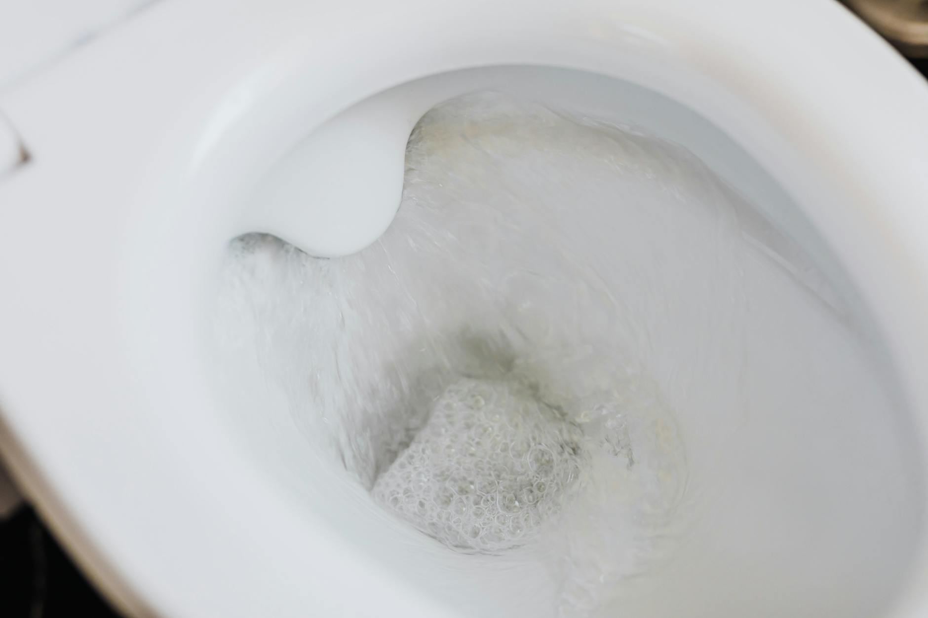 flushing water in white toilet bowl