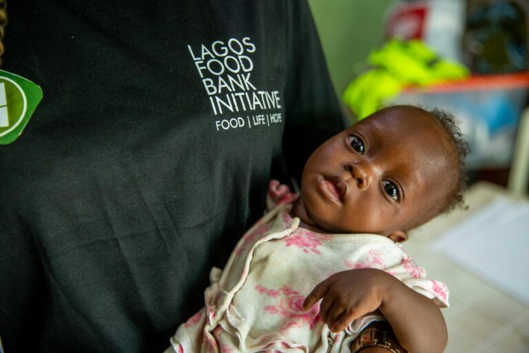 a person in black shirt carrying a baby in pink and white shirt